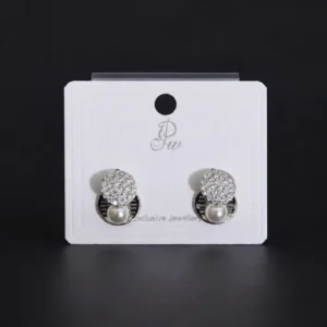 Pair of silver-toned geometric stud earrings featuring a round crystal pave disc and a small white pearl drop on a display card.
